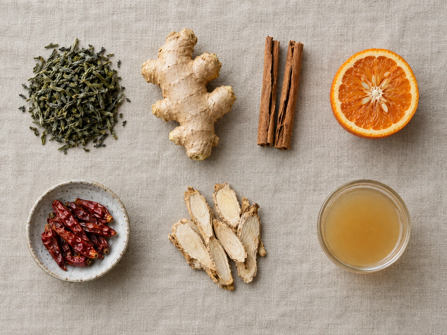 Feuilles de thé vert, gingembre, bâtons de cannelle de Ceylan, orange amère coupée, piments séchés, rondelles de ginseng et vinaigre de cidre sur du lin